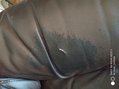 Canapé cuir noircit, craquelé et troué par tête