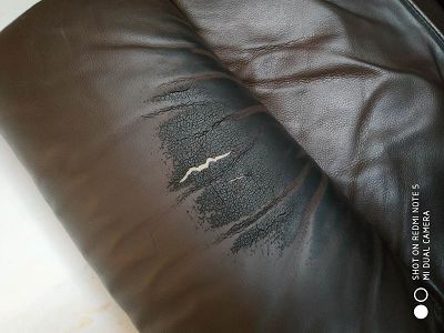 Canapé cuir noircit, craquelé et troué par tête